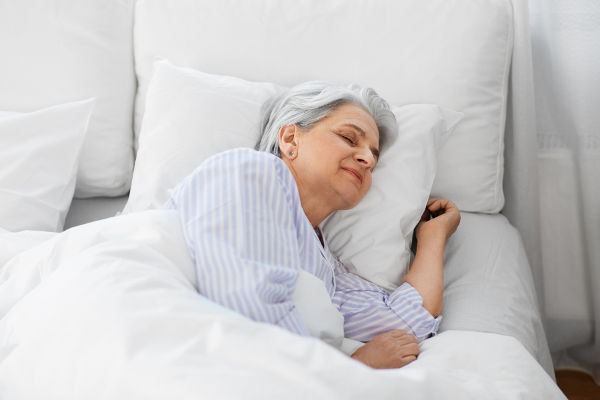 Une personne âgée qui dort confortablement dans un lit